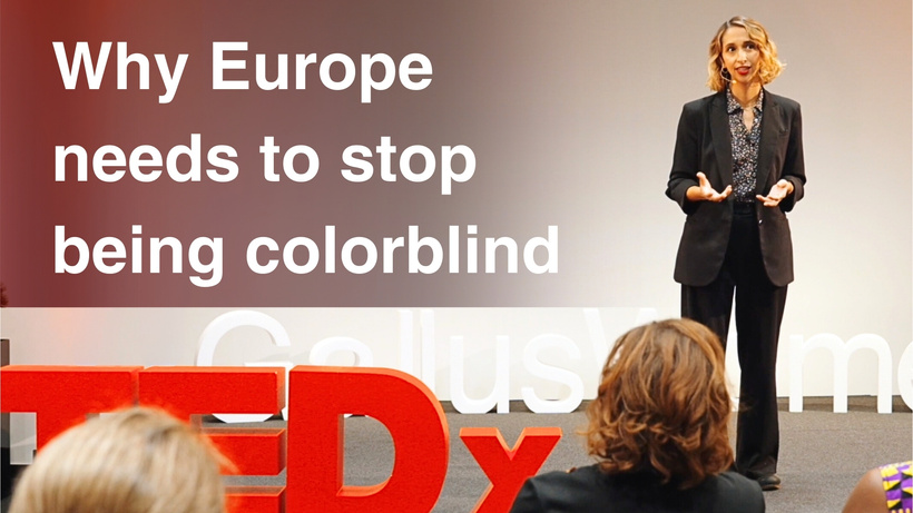 Image of M.K. Kirigin speaking at a TED X conference with the title "why Europe needs to stop being colorblind"